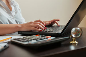 A person typing on a laptop using Quicken or Quickbooks for small business finances.