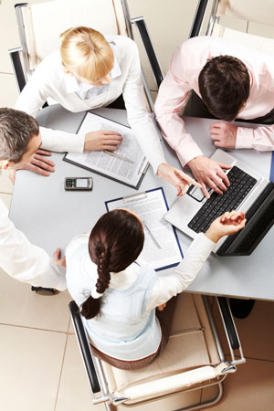 4 small business employees gather around a table to make a financial plan.