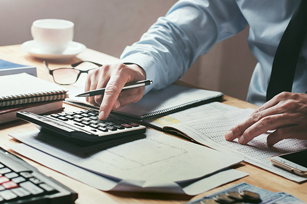 A person managing their small business finances with a calculator.