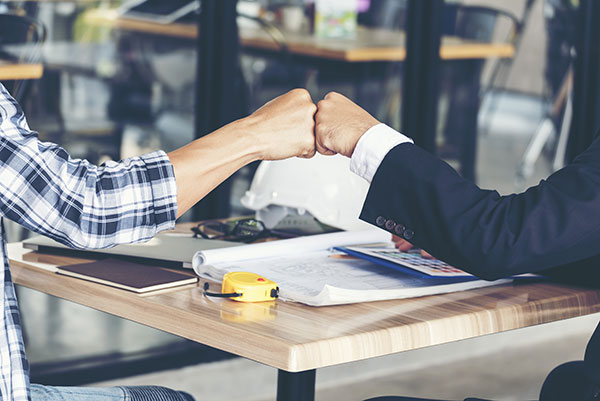 Two people fist-bumping after closing a deal.