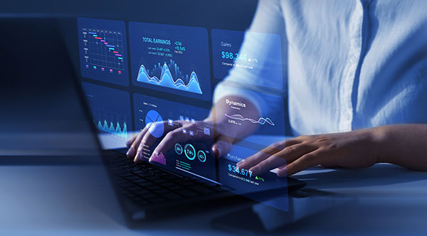 A person working on a laptop with a holographic screen reflection of charts.