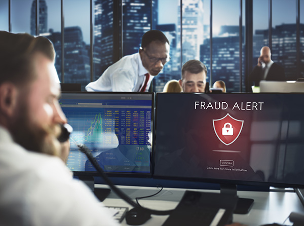 Business leader on the phone discussing a fraud alert notification on his computer.