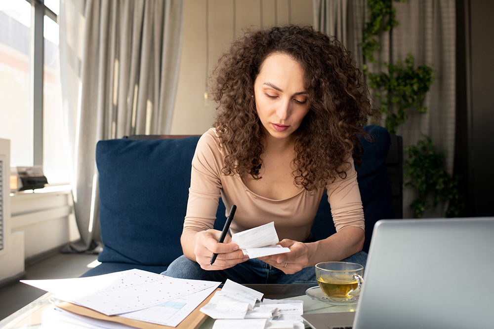 A woman sorting through receipts as she works in her home.