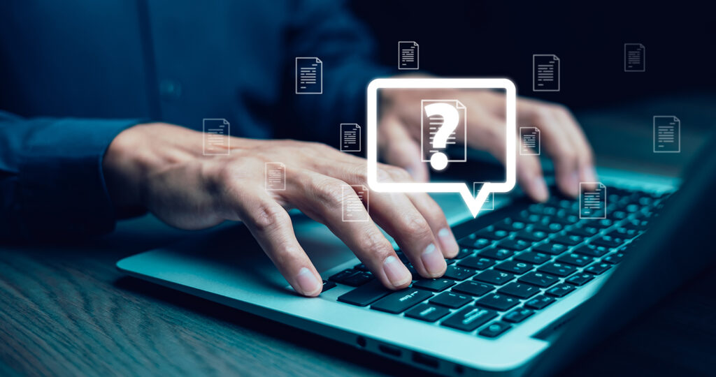 Hands typing on a laptop keyboard. There is a white question mark inside a chat box that's overlayed on the image. This image represents business cyber security FAQs.