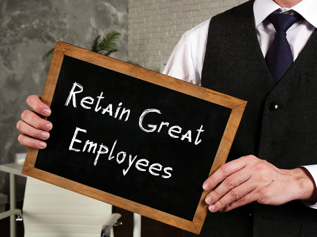 man in a tie holding a chalkboard that says, "Retain Great Employees."
